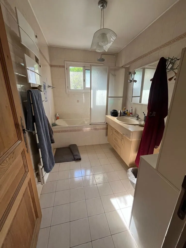 Salle de bains avant rénovation avec baignoire, paroi de douche en verre dépoli et meuble vasque