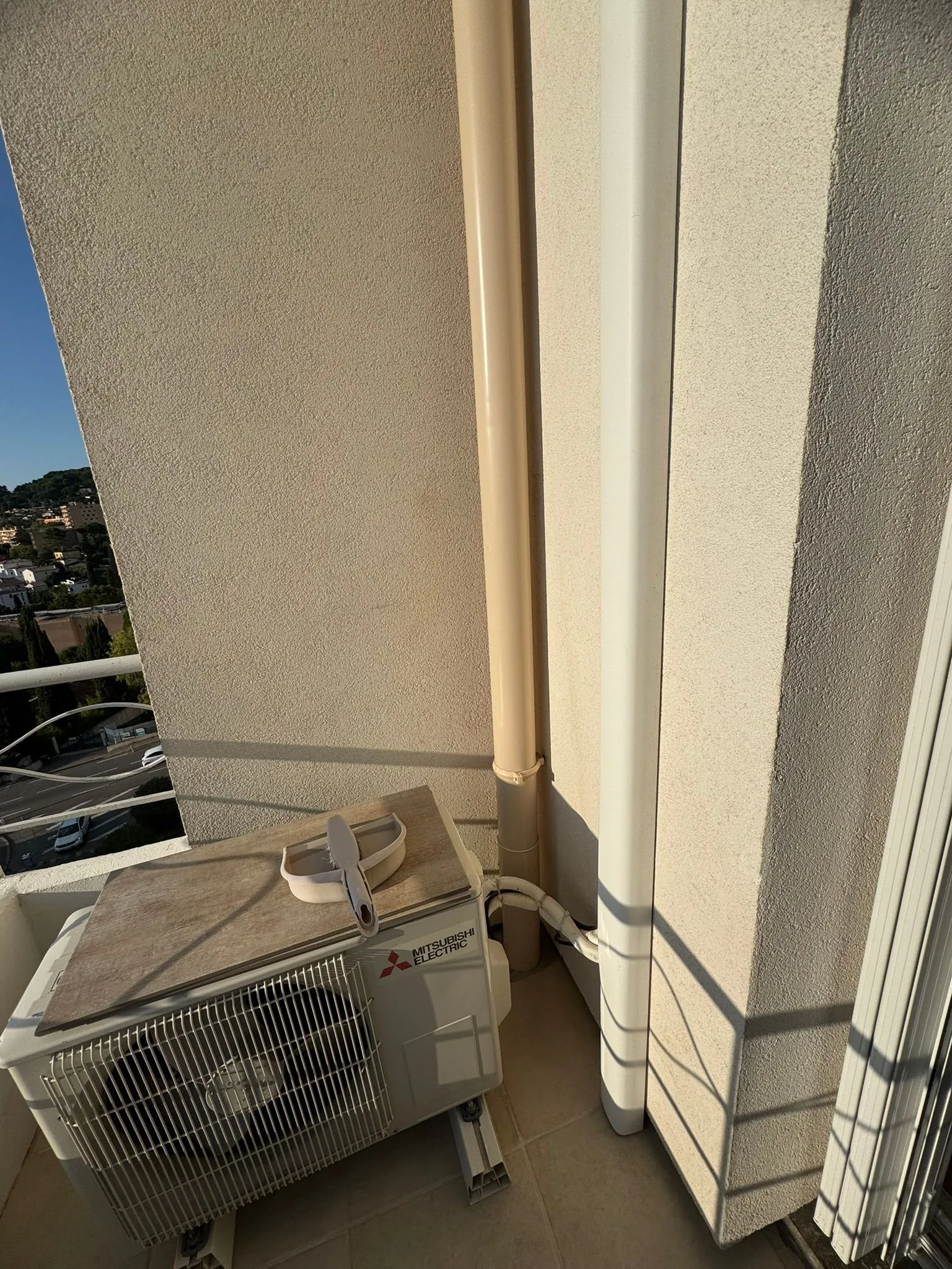 Descente d'eau pluviale beige remise en état le long d'un mur crépi sur un balcon