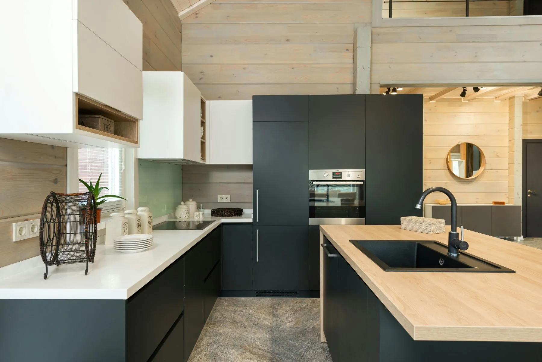 Cuisine ouverte aux meubles noir mat et blancs, îlot en bois avec évier noir et mitigeur noir