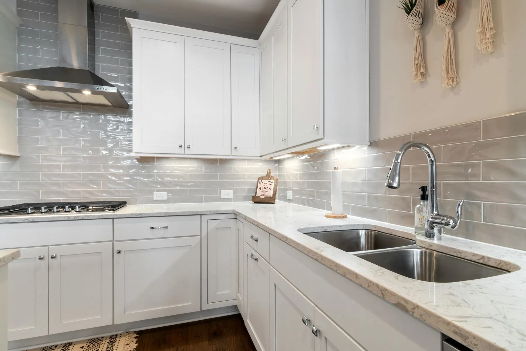 Cuisine blanche avec double évier inox encastré dans un plan de travail en quartz et mitigeur chromé