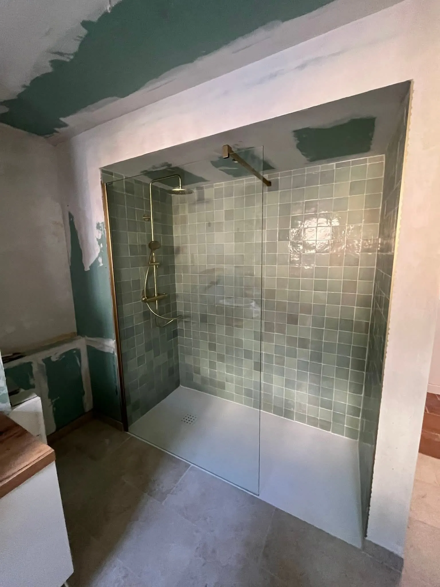 Douche à l'italienne avec receveur blanc extra-plat, paroi de verre et colonne de douche dorée