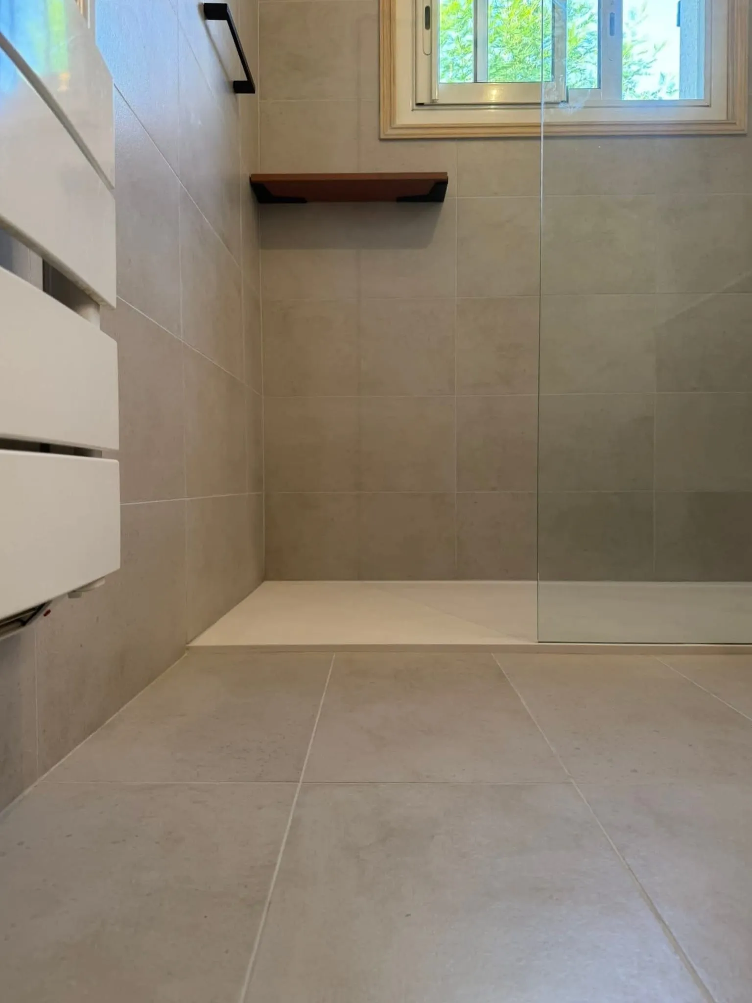 Douche à l'italienne avec receveur extra-plat, paroi de verre et carrelage grand format gris