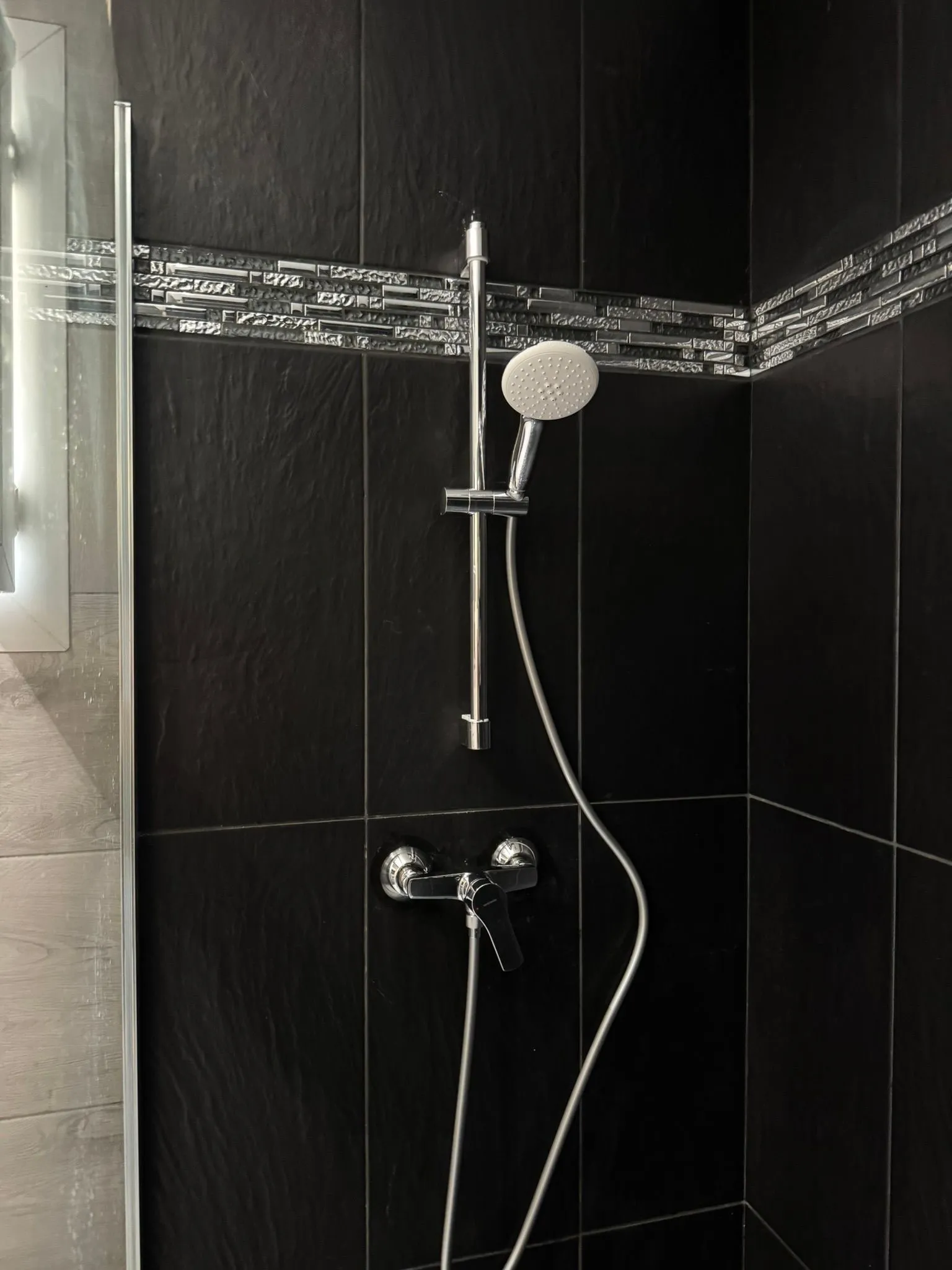 Mur de douche en carrelage noir ardoisé avec frise de mosaïque métallique