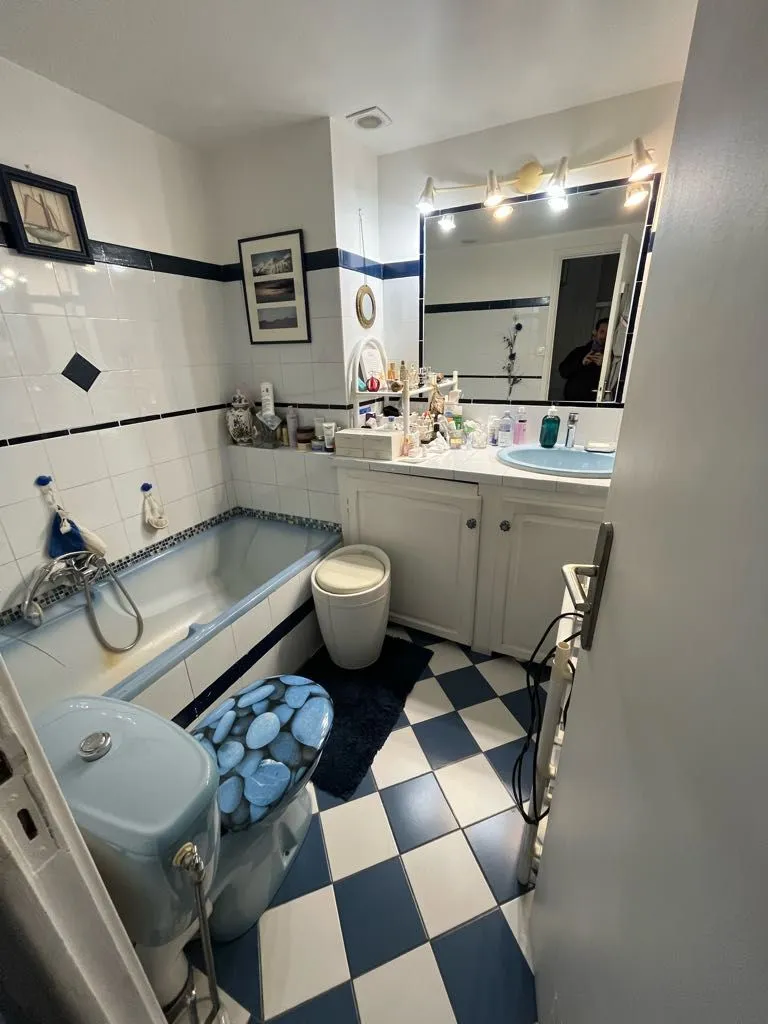 Salle de bains avant travaux avec sanitaires bleus, baignoire et carrelage damier