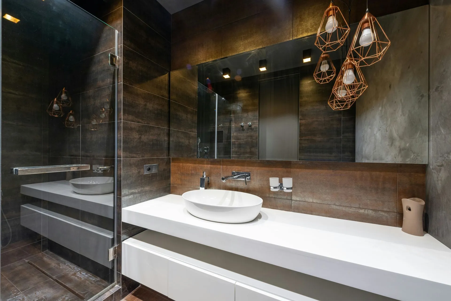 Salle de bains moderne aux murs bruns effet métal avec vasque ovale blanche sur plan suspendu
