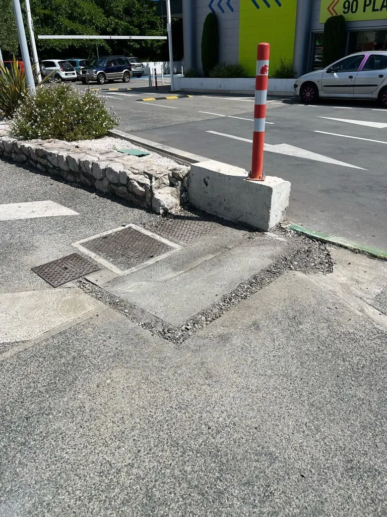 Parking après intervention : tranchée rebouchée et revêtement refait autour des plaques