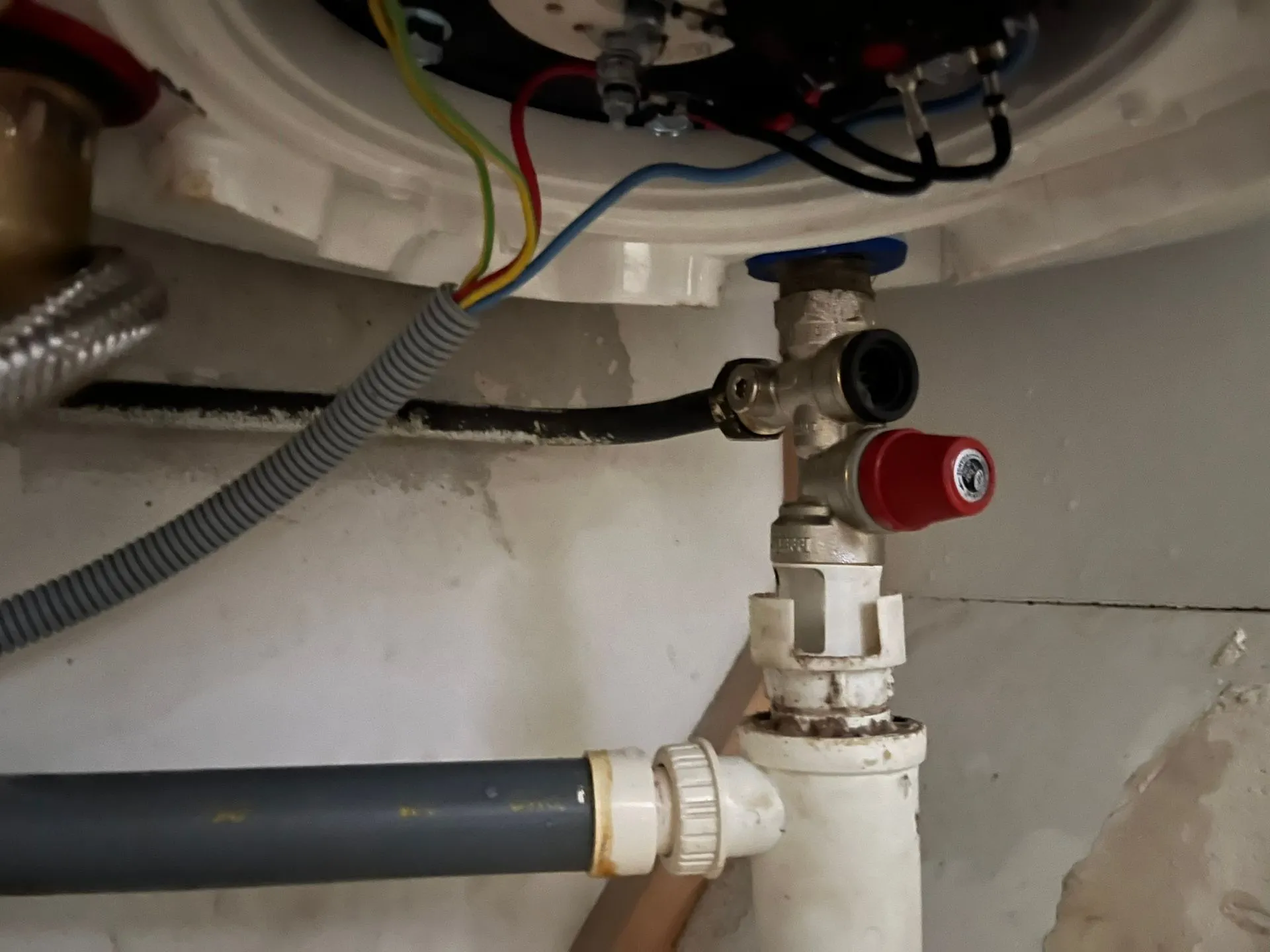 Dessous d'un chauffe-eau électrique montrant le groupe de sécurité à capuchon rouge