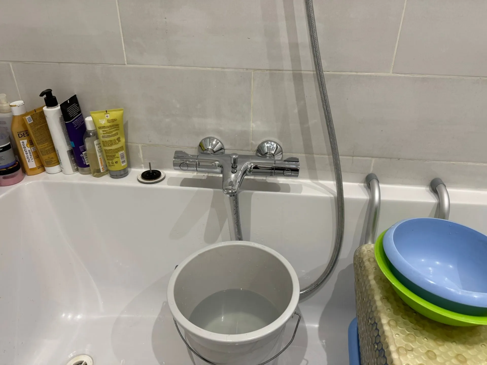Baignoire blanche avec mitigeur thermostatique chromé fixé au mur carrelé gris